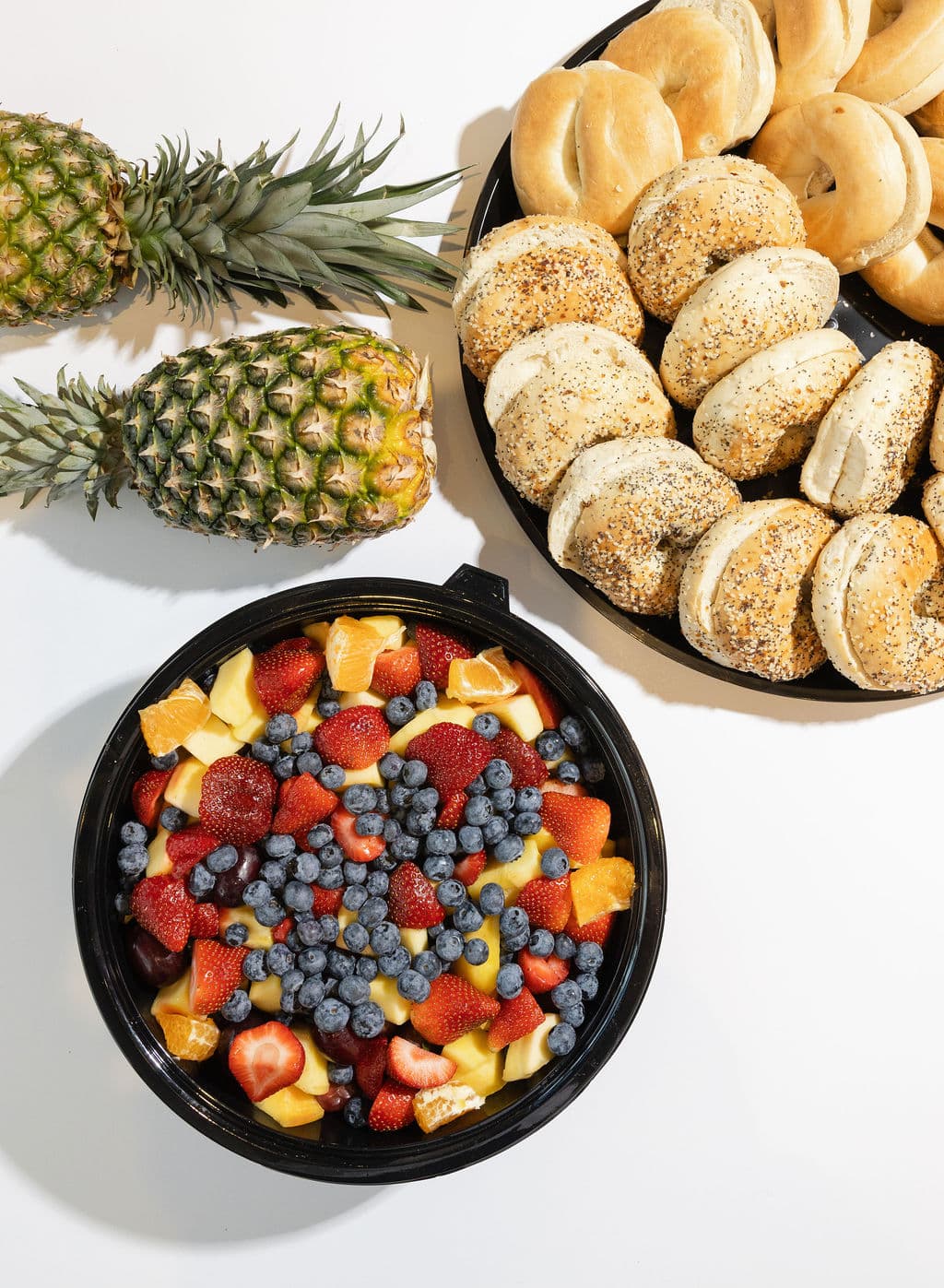 Comfort Fuel catering spread — bagel platter, fresh fruit bowl, and pineapple